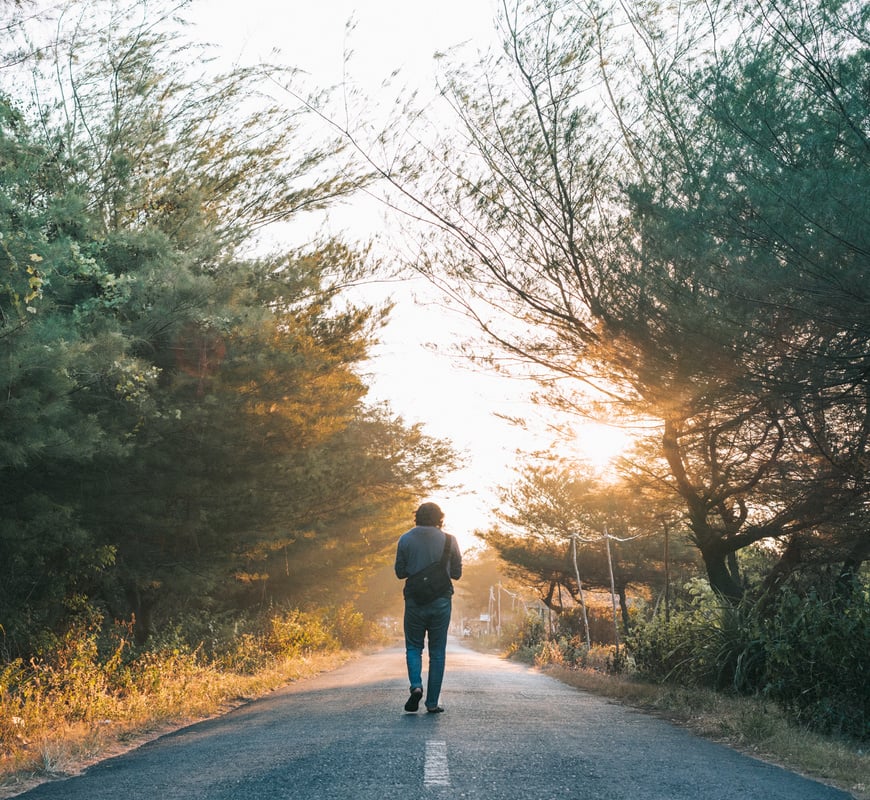 Man Walking on the Gray Asphalt Road